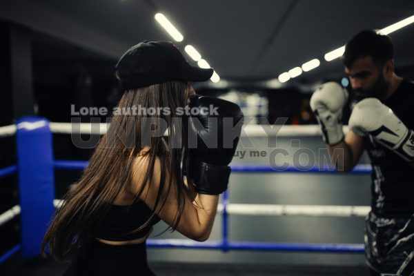 A girl in boxing training at the ring with a trainer