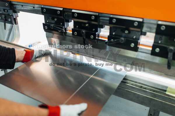 Factory_worker_bending_steel_at_the_machine