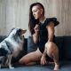 An attractive woman with a sheltie dog is playing on the sofa. Young lady with her pet at home