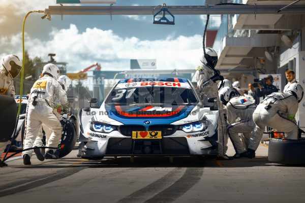 BMW M4 DTM Tom Blomqvist Team RBM on the pit stop. Mechanics of BMW racing team change tyres at the pitline during pitstop