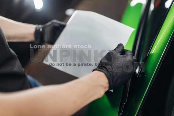A man makes a detailing of a new car and use a steam to wrap a mirror