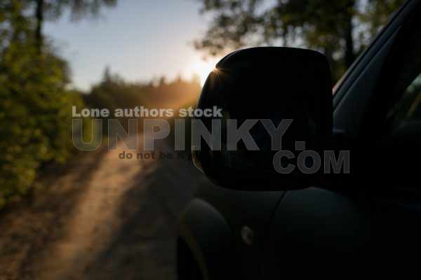 Car in forest at the evening . Sun rays of sun and mirror silhouette. Sunrise in tropics during off-road trip