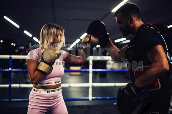 A girl in boxing training at the ring with a trainer