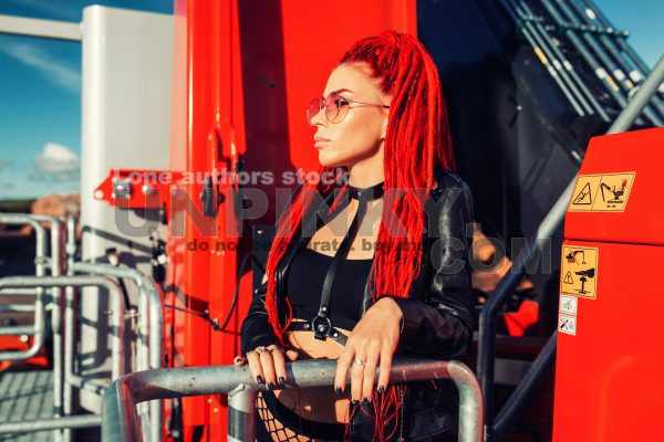 Beautiful girl with dreadlocks and red hair at a construction site