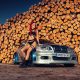 Sexy woman with red hair sitting on the fender of sportcar