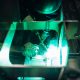 The master makes spot welding of metal parts in the factory, sparks, and glow. Man cut off metal construction