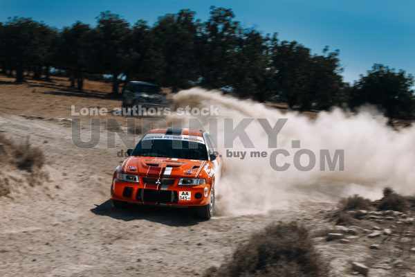 Mitsubishi Lancer Evolution 5 in motion with clouds of dust. The Rally car makes a turn at the high speed
