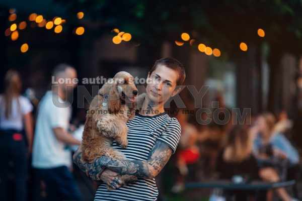 Tattoed woman holding cocker spaniel at the hands