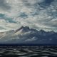 Snowy mountains in the distance. Dramatic view on winter landscape with mountains and rock, covered with snow. Heavy clouds above ski resort
