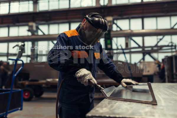 Factory worker polish and cut off a metal part