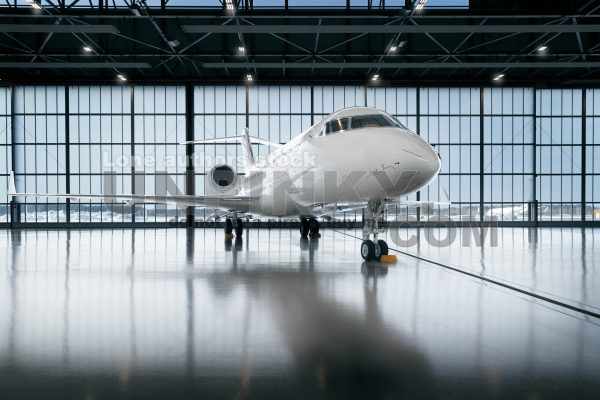 Private jet airplane at the huge white hangar waiting for a maintenance or passengers