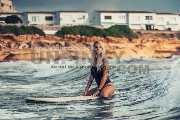 Young beautiful woman relaxing in the sea on a surf board