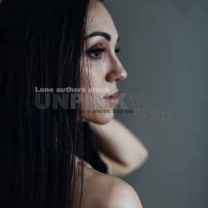 Naked woman with long hair stands against the wall. Beautiful lady at the empty room early morning