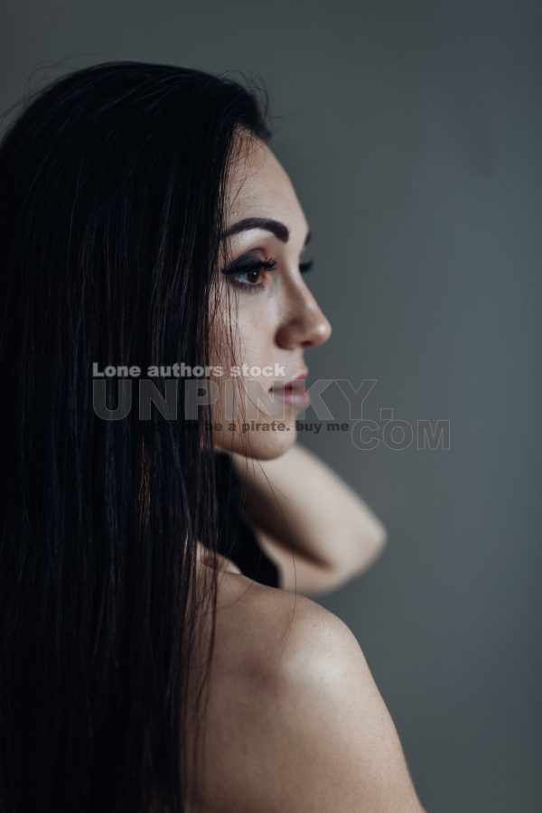 Naked woman with long hair stands against the wall. Beautiful lady at the empty room early morning