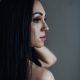 Naked woman with long hair stands against the wall. Beautiful lady at the empty room early morning