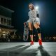 Girl holding a skateboard at night in the spotlights