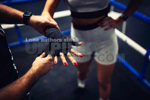 Trainer help to tape woman hand with a sport belt before kickbox