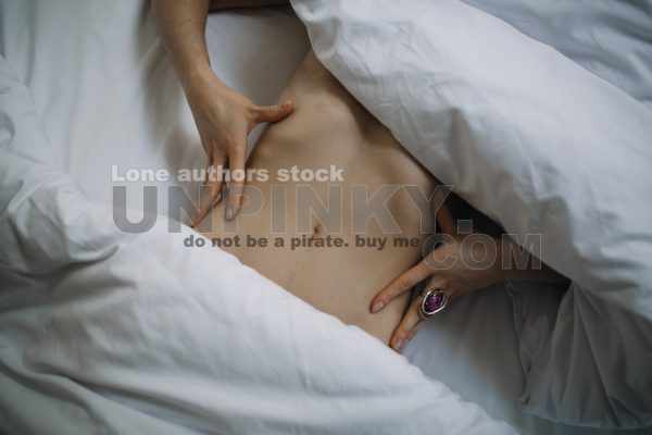The girl lies under the blanket, part of her abdomen is covered with a cloth