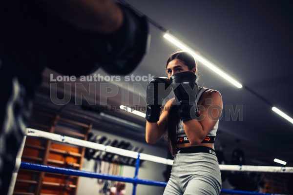 A girl in boxing training at the ring with a trainer