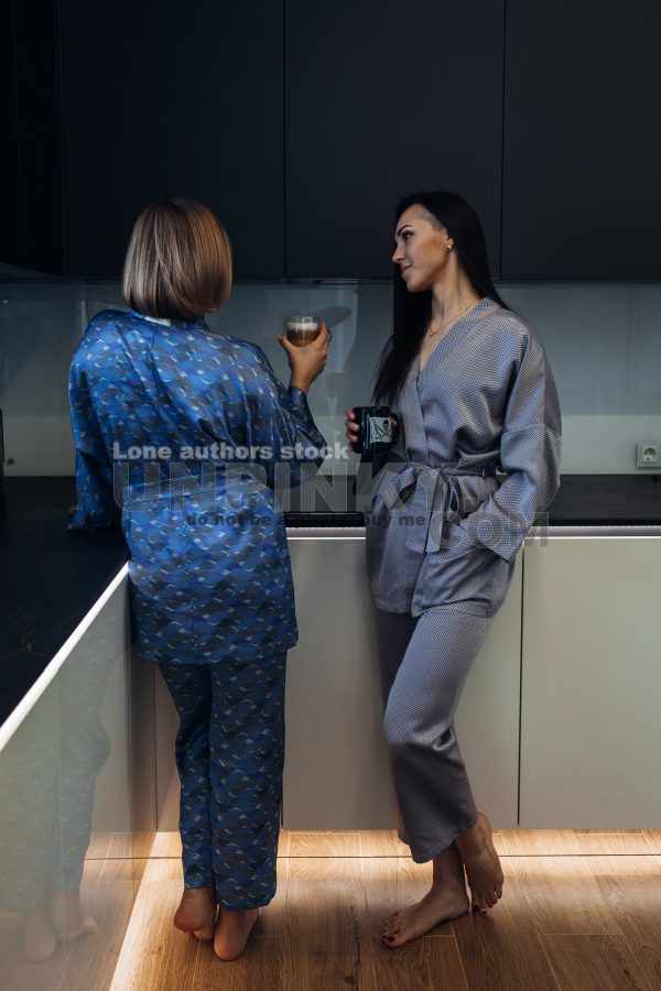 Stylish young woman relaxing in a modern kitchen with coffee in the morning. Modern kitchen with backlight. Lady is resting before working day