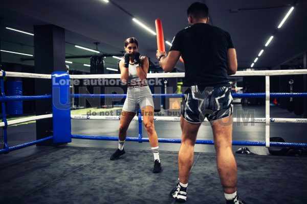 A girl in boxing training at the ring with a trainer