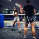 A girl in boxing training at the ring with a trainer