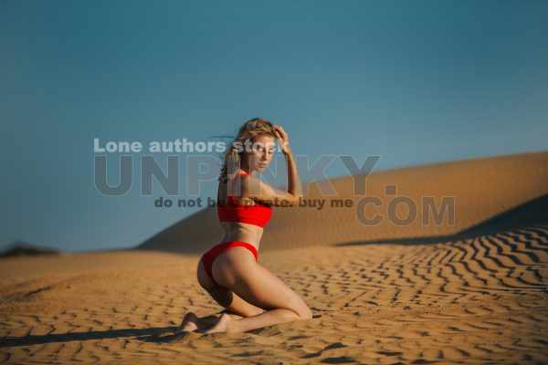 Beautiful fitness woman in red swimsuit is sitting in the middle of desert