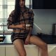 Stylish young woman relaxing in a modern kitchen with coffee in the morning. Modern kitchen with backlight. Lady is resting before working day