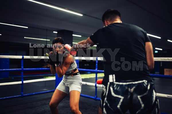 A girl in boxing training at the ring with a trainer
