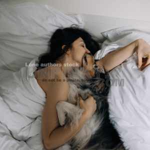 Attractive women wake up in the morning with a dog in the modern bright bedroom. Pet on the bed. Lady is waking up early morning with her dog.