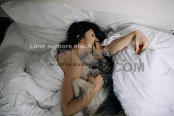 Attractive women wake up in the morning with a dog in the modern bright bedroom. Pet on the bed. Lady is waking up early morning with her dog.