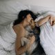 Attractive woman wake up in the morning with a dog in the modern bright bedroom. Pet on the bed. Lady is waking up early morning with her dog.