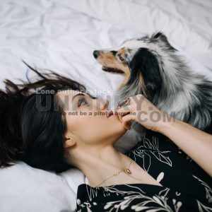 Attractive women wake up in the morning with a dog in the modern bright bedroom. Pet on the bed. Lady is waking up early morning with her dog.