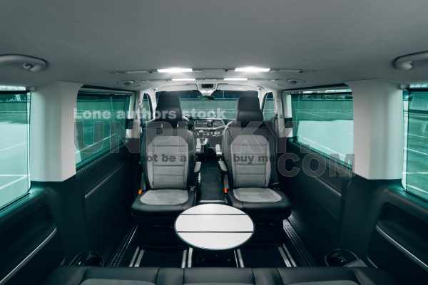 Interior of the luxury van with comfortable leather seats and table. VIP transfer cars with modern backlights and seats are waiting for a passengers