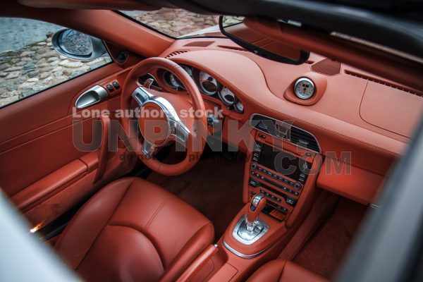 Supercar interior, view through sunroof. Close up view of expensive car interior with comfortable leather seats and dashboard