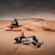 Woman with long hair sitting at the sands, and motorcycle rider go fast at the dune | ART