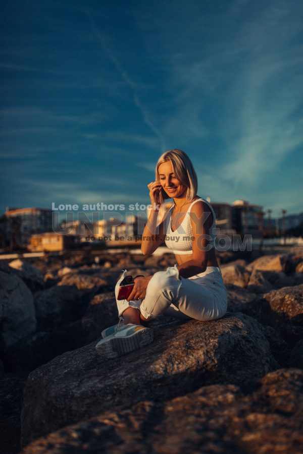 A Stunning Woman Enjoys the Tranquil Sunset by the Sparkling Sea, Embracing the Calming Moment of Nature's Majesty
