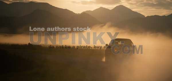 Pickup truck car drive fast at the country road with clouds of dust and beautiful mountains at the background. Sunrise in valley with a steam. Panoramic view with free space for text